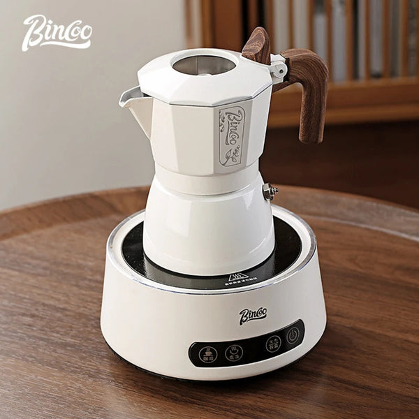 White coffee maker with wooden handle on a wooden table, featuring the Binco brand.