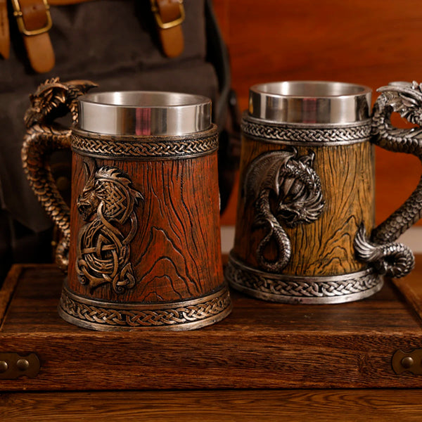 Two 500ml medieval dragon barrel tankard mugs with 304 stainless steel liners, one in dark reddish-brown wood finish with a bronze dragon emblem and one in light oak finish with a silver dragon emblem.