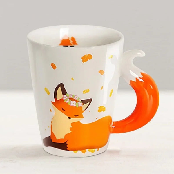 White ceramic 380ml coffee mug featuring a sleeping cartoon fox wearing a flower crown surrounded by autumn leaves, with a sculpted orange and white 3D fox tail handle.