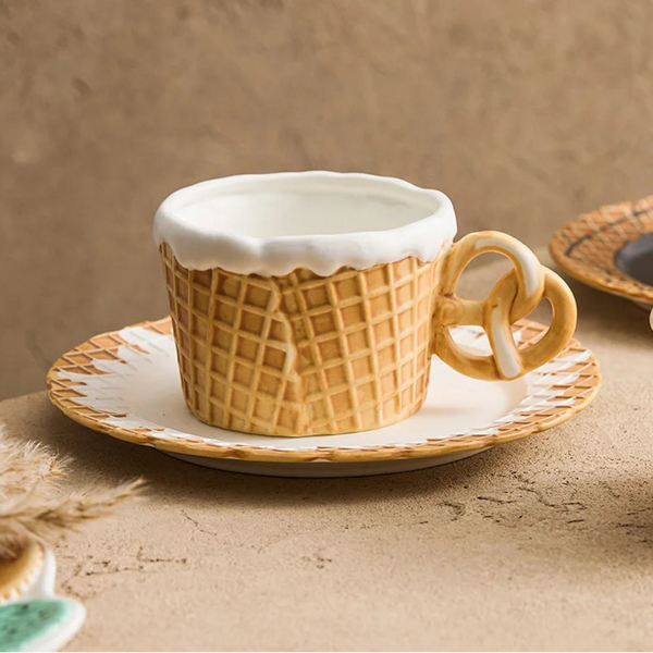Tan waffle-pattern ceramic mug with a realistic pretzel handle and a matching scalloped biscuit-edge saucer plate.
