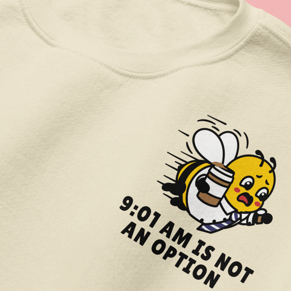 Close-up detail of the left chest embroidery on the oatmeal cream crewneck sweatshirt, showing a funny mascot bee rushing with a coffee cup and the bold text "9:01 AM IS NOT AN OPTION."
