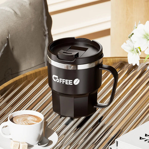 Matte black insulated coffee mug with handle on a slatted wooden table at an outdoor cafe
