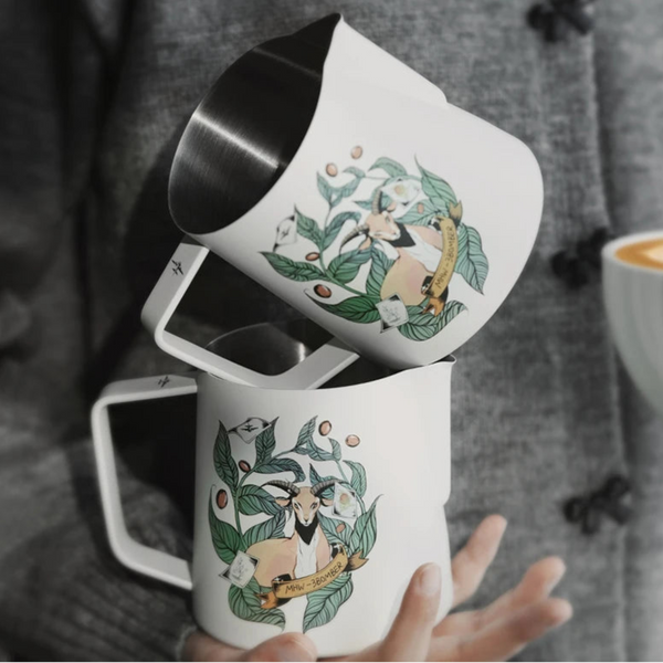 Two MHW-3BOMBER Origin Series milk pitchers in cream white featuring the Kaldi goat illustration and ergonomic handle.