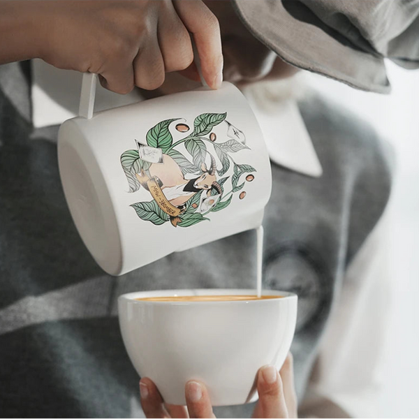 Barista using a white MHW-3BOMBER Origin Series pitcher to pour milk into a cup for precision latte art.