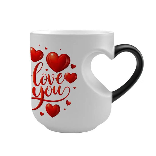 A white ceramic mug with a heart-shaped handle, featuring a red graphic print of the words 'I love you' surrounded by red hearts, set against a plain white background.